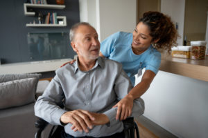 Senior man in a wheelchair talking to his home caregiver