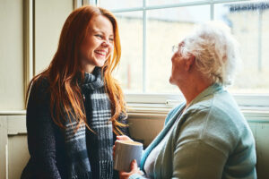 Young caregiver talking to senior woman about advantages of home care.