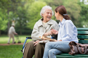 Family caregiver sitting on a park bench with senior loved one