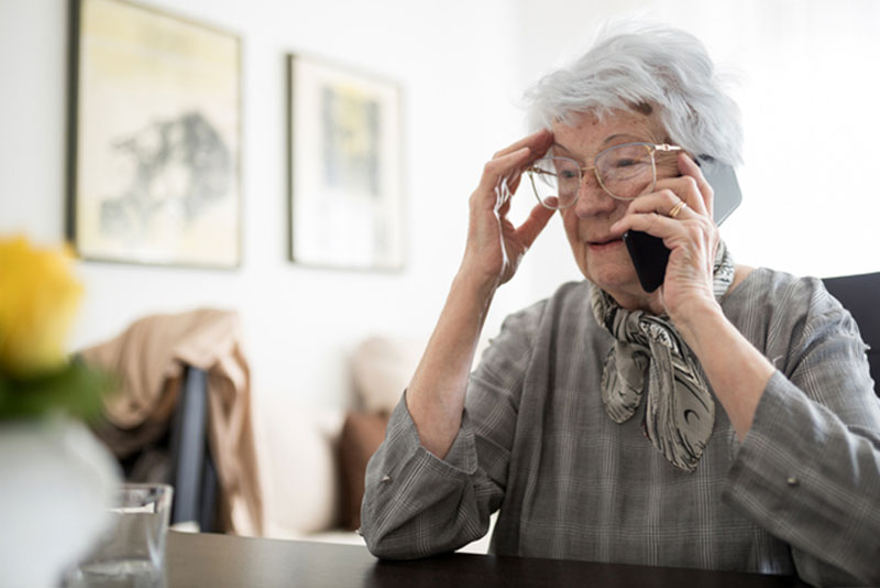 confused senior lady on phone at desk