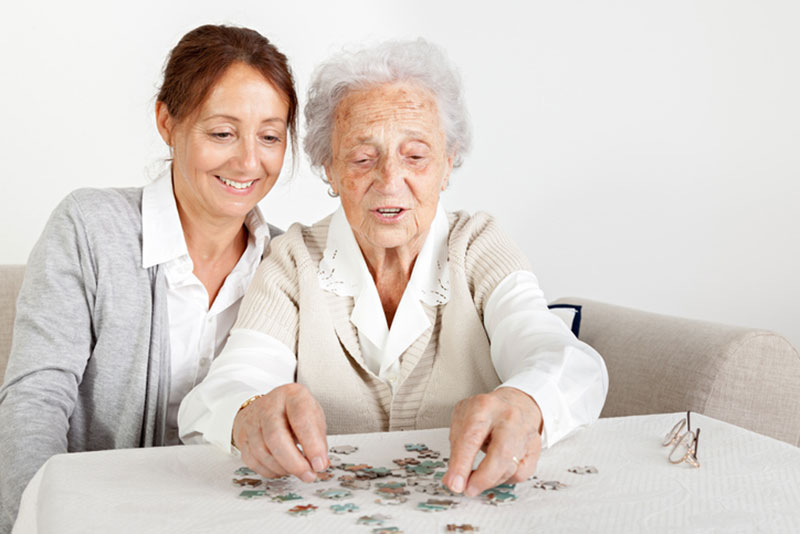 A woman does a puzzle with her elderly mother, one of a number of activities for dementia patients that can boost self-confidence.