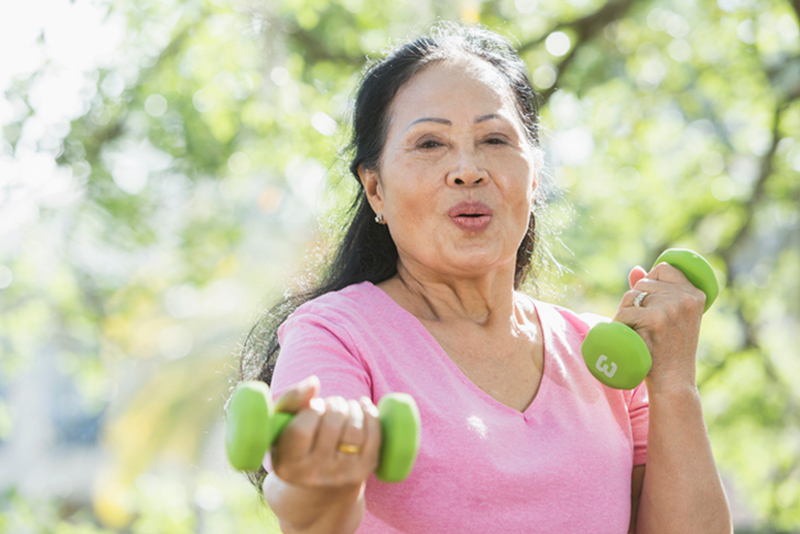 A woman uses hand weights knowing that exercise is a key strategy to prevent a stroke.