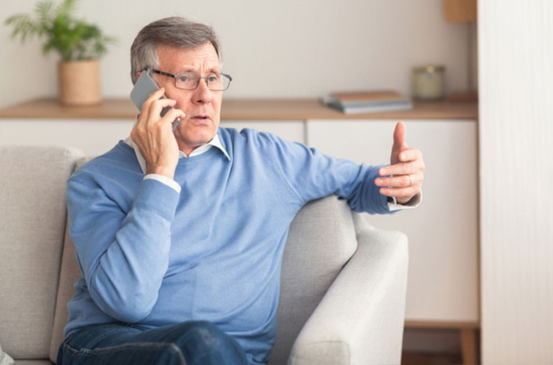 A man is cautious when speaking on the phone because he knows the risks of elder fraud.
