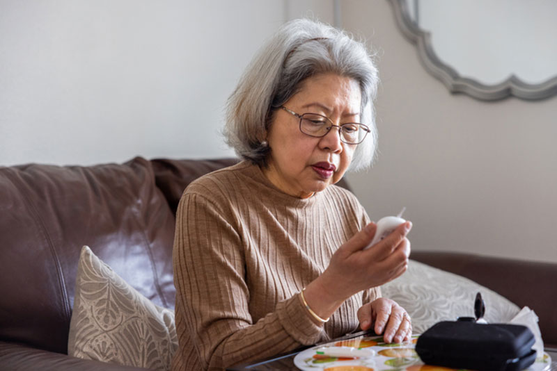 An elderly woman checks her blood sugar. Monitoring blood sugar levels is a crucial part of diabetes management.